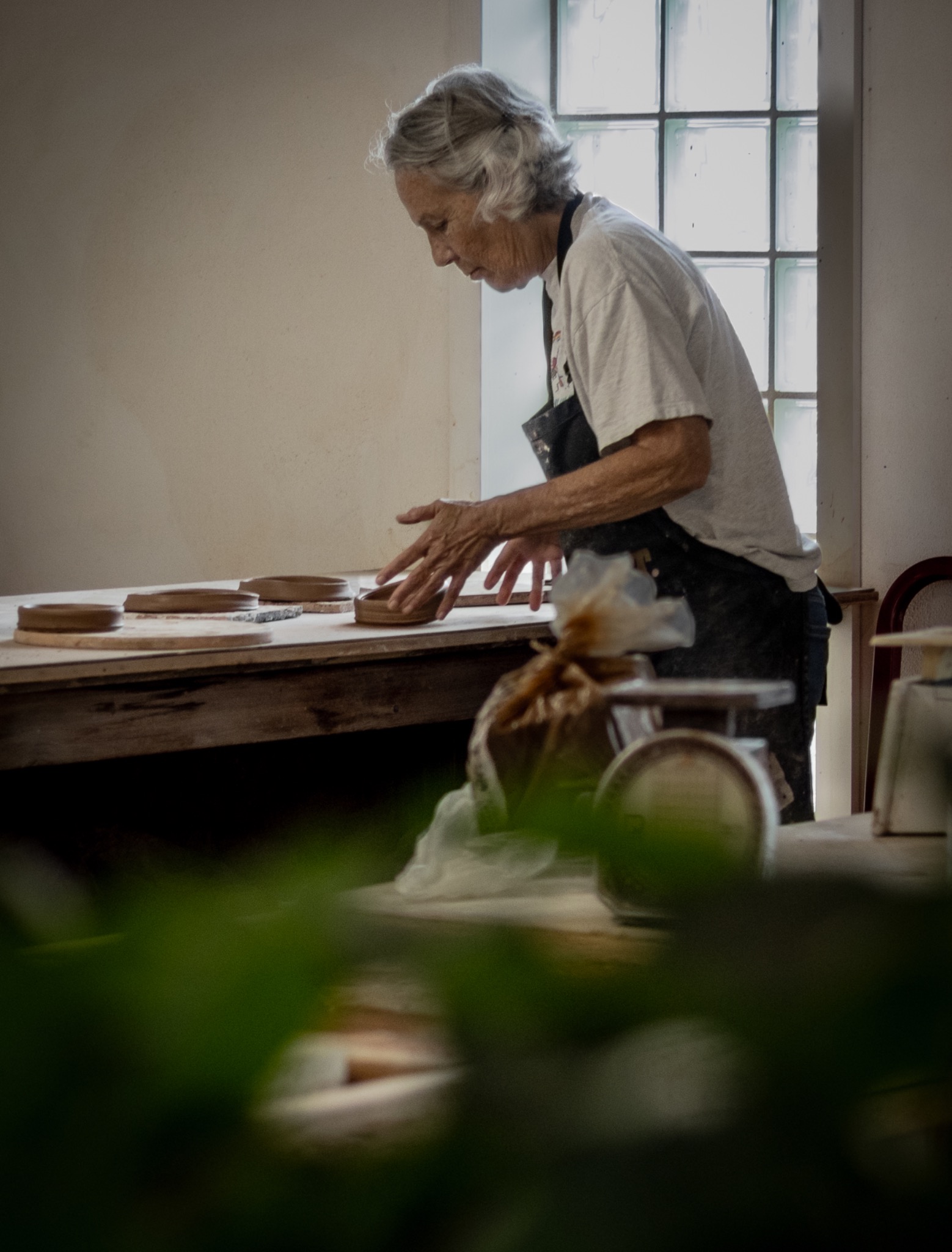 A ceramic artist working beside a bright studio window