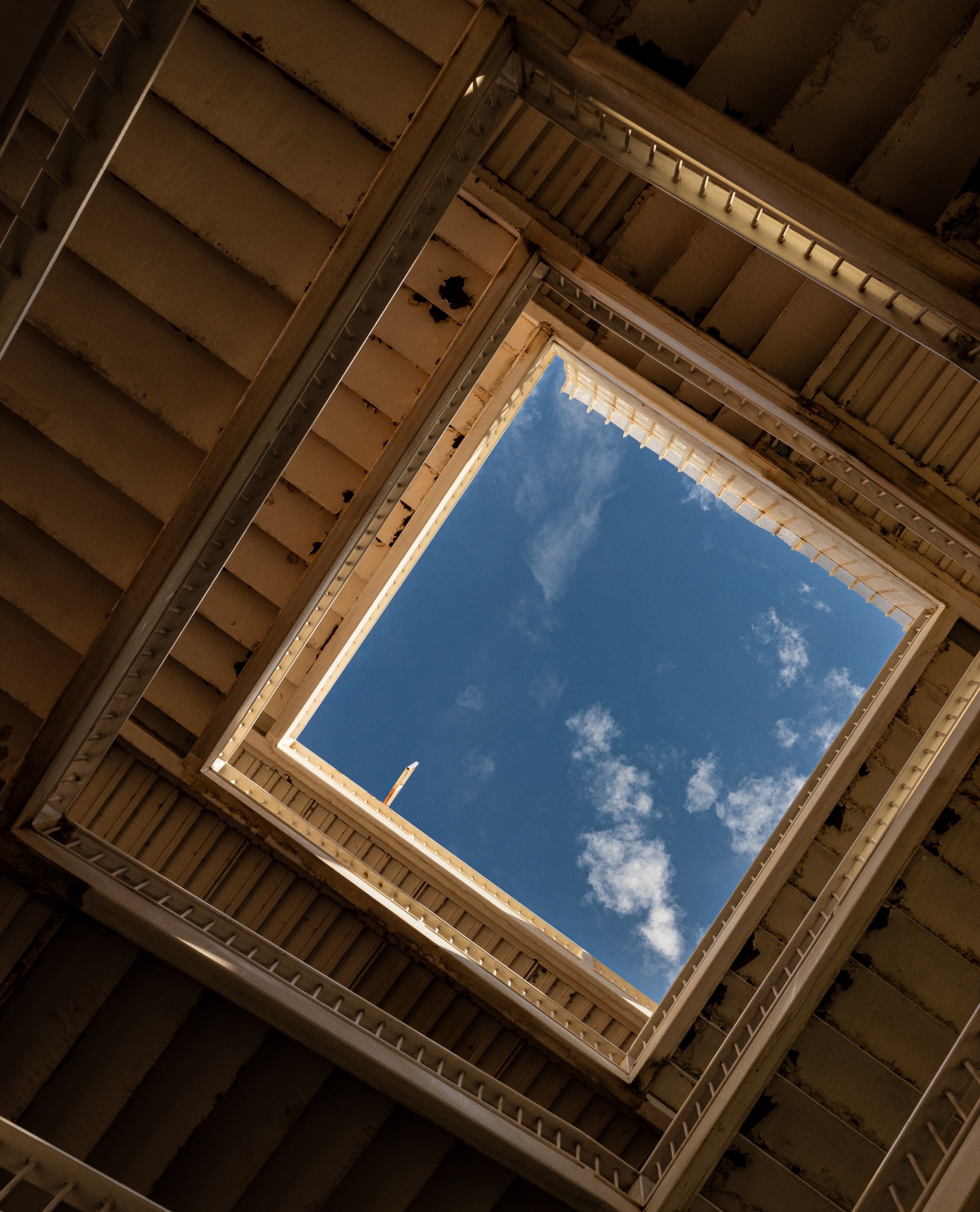Stacked stair flights frame a rectangular opening of blue sky